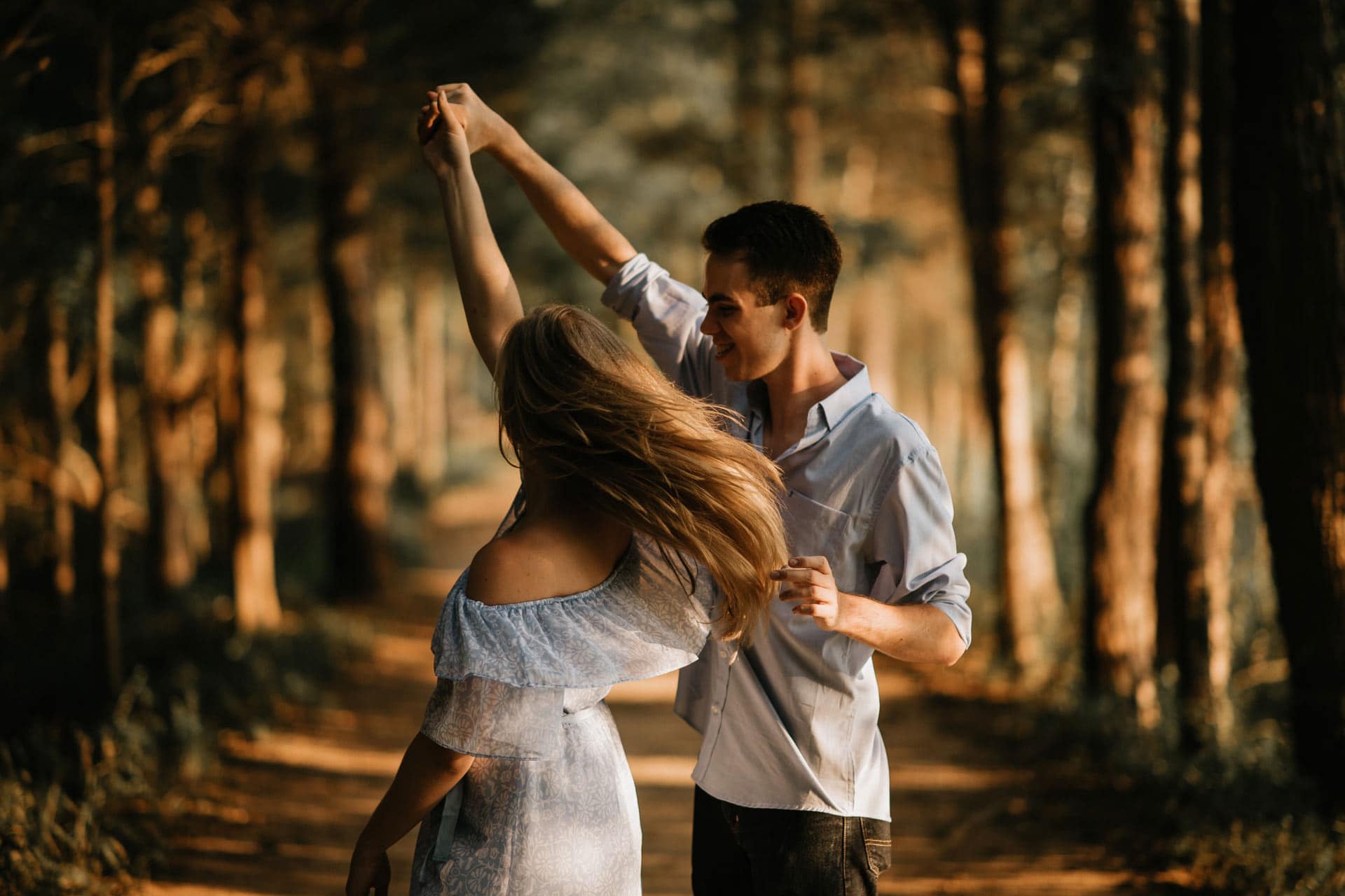 Romantic couple dancing in the woods at sunset for engagement or wedding photos.