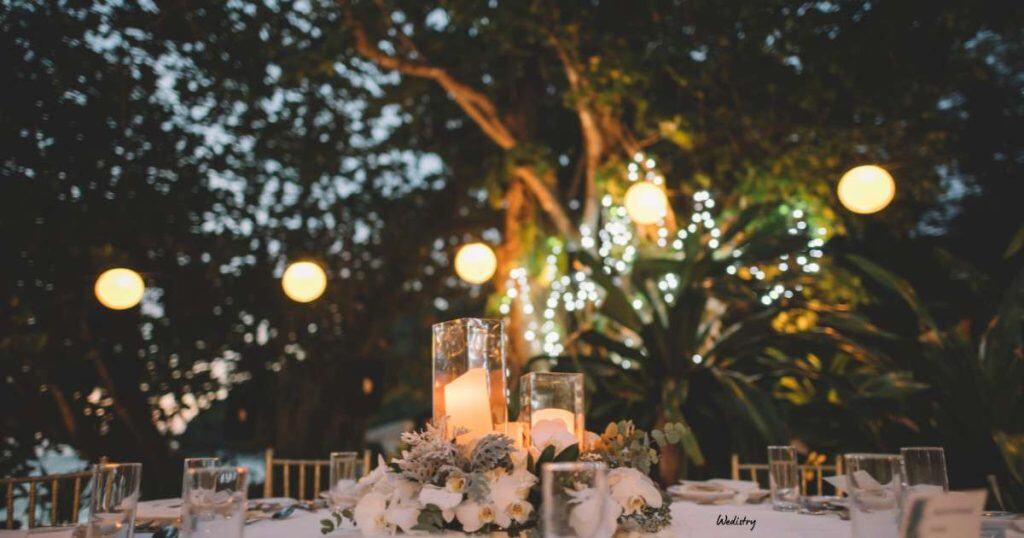Elegant outdoor wedding table setup with candles and floral decor at dusk.
