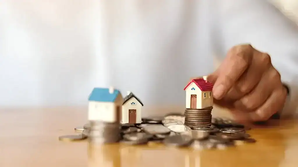 Miniature houses on coins representing real estate investment and financial planning.