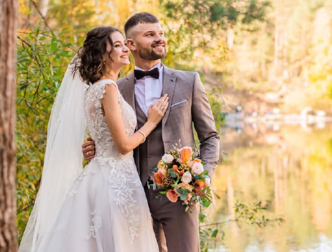 Elegant bride and groom outdoor wedding portrait at sunset, celebrating love by the lake.